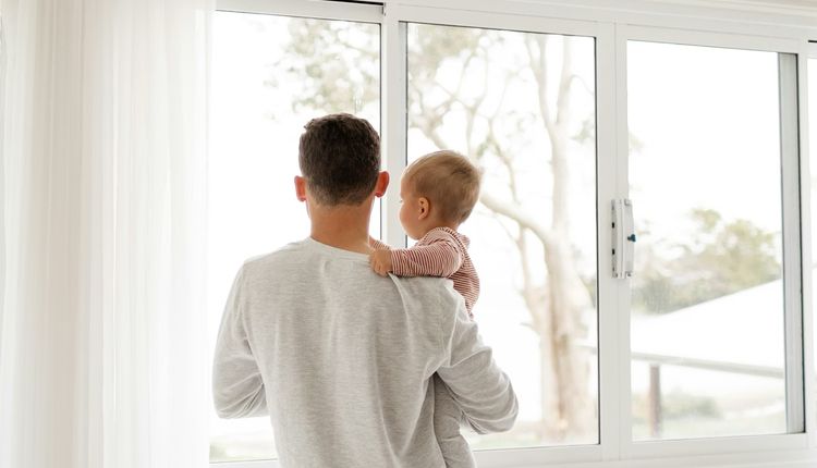 Father holding a baby looking out the window